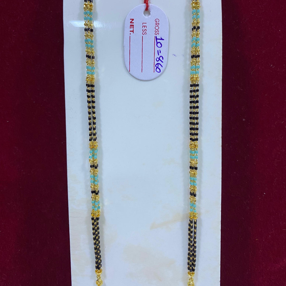 Two beaded necklaces on a white stand with a red background