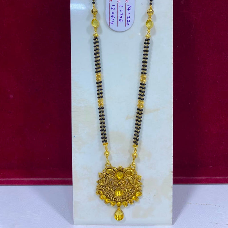 A traditional Indian gold and black beaded necklace with a detailed gold pendant, displayed on a white stand against a dark red background.