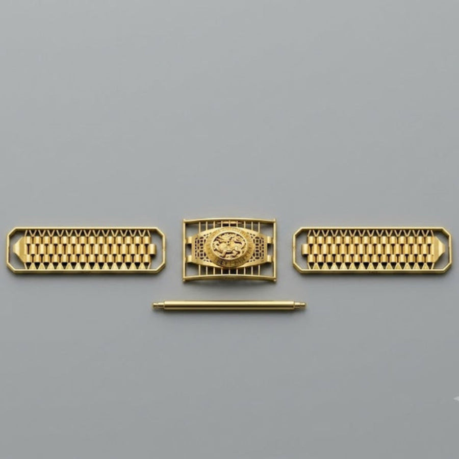 A set of gold-toned mechanical watch components or decorative hardware pieces arranged horizontally on a plain gray background, including two rectangular grids with small circular elements and a central rectangular piece with a circular emblem, plus a thin horizontal rod below.