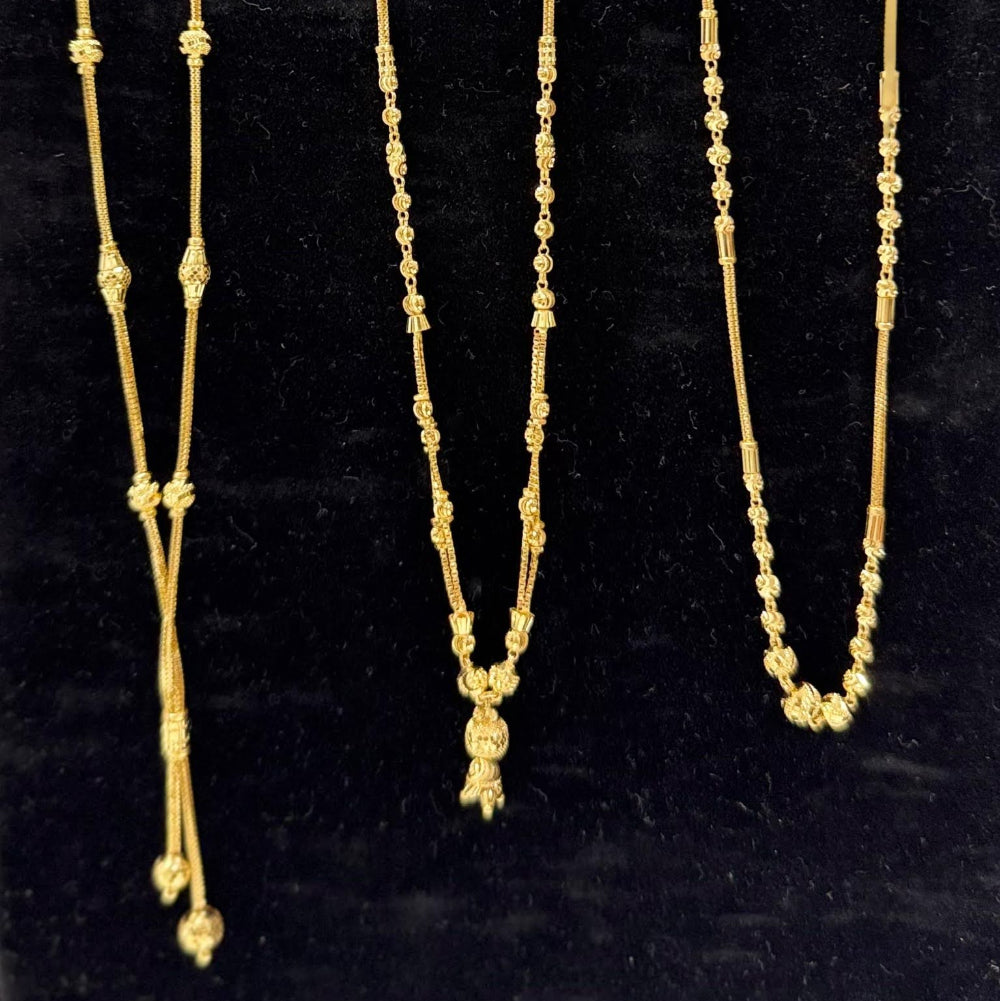 Three gold necklaces on a black stand