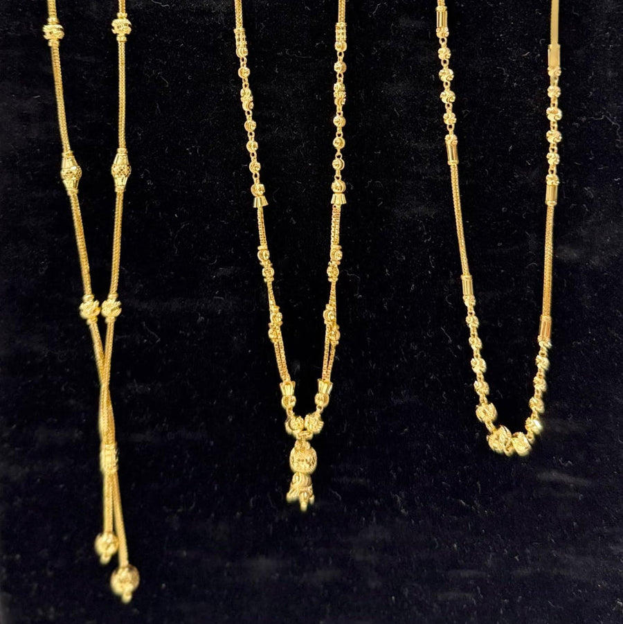 Three gold necklaces on a black stand