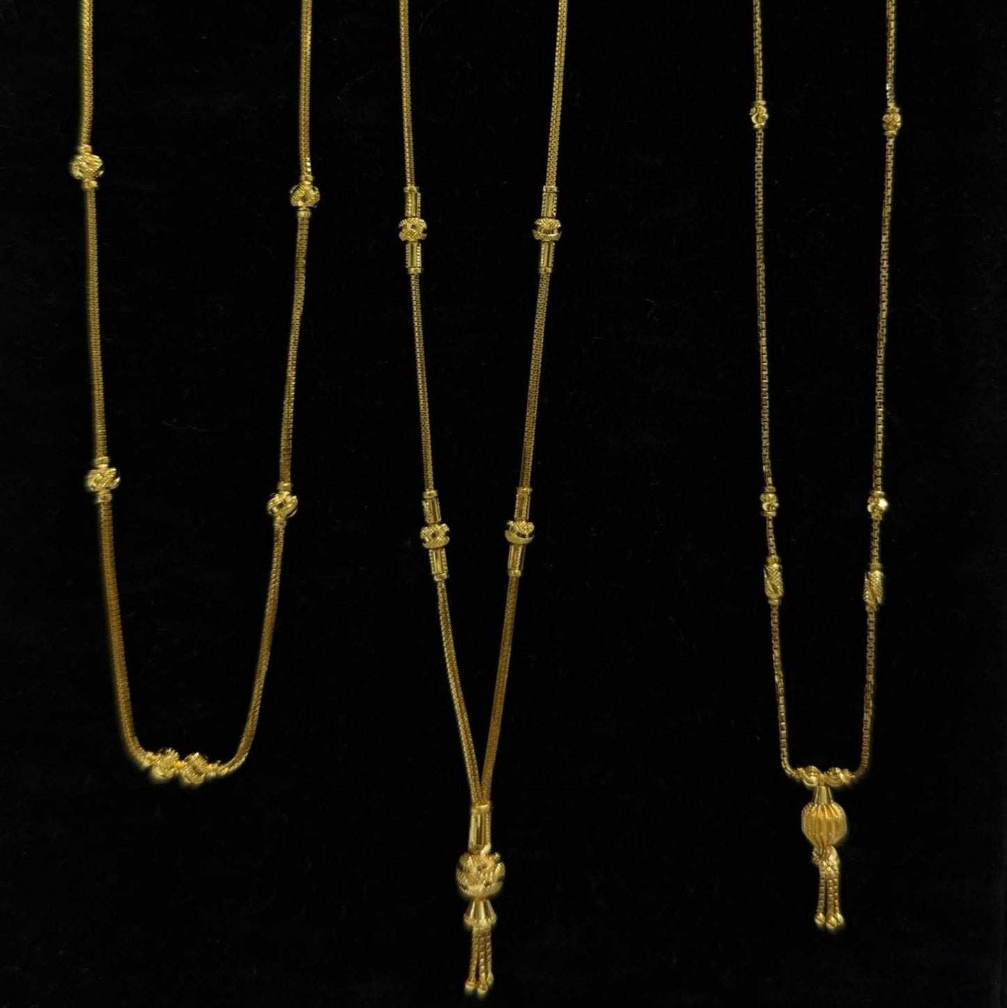 Three gold necklaces on a black stand