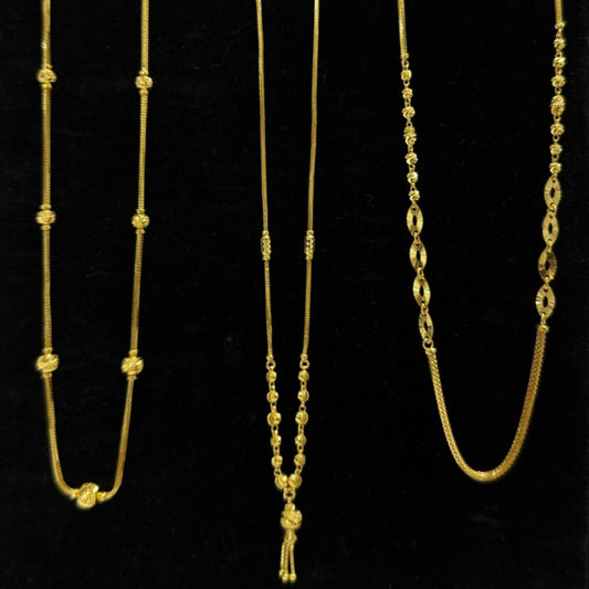 Three gold necklaces on a black stand