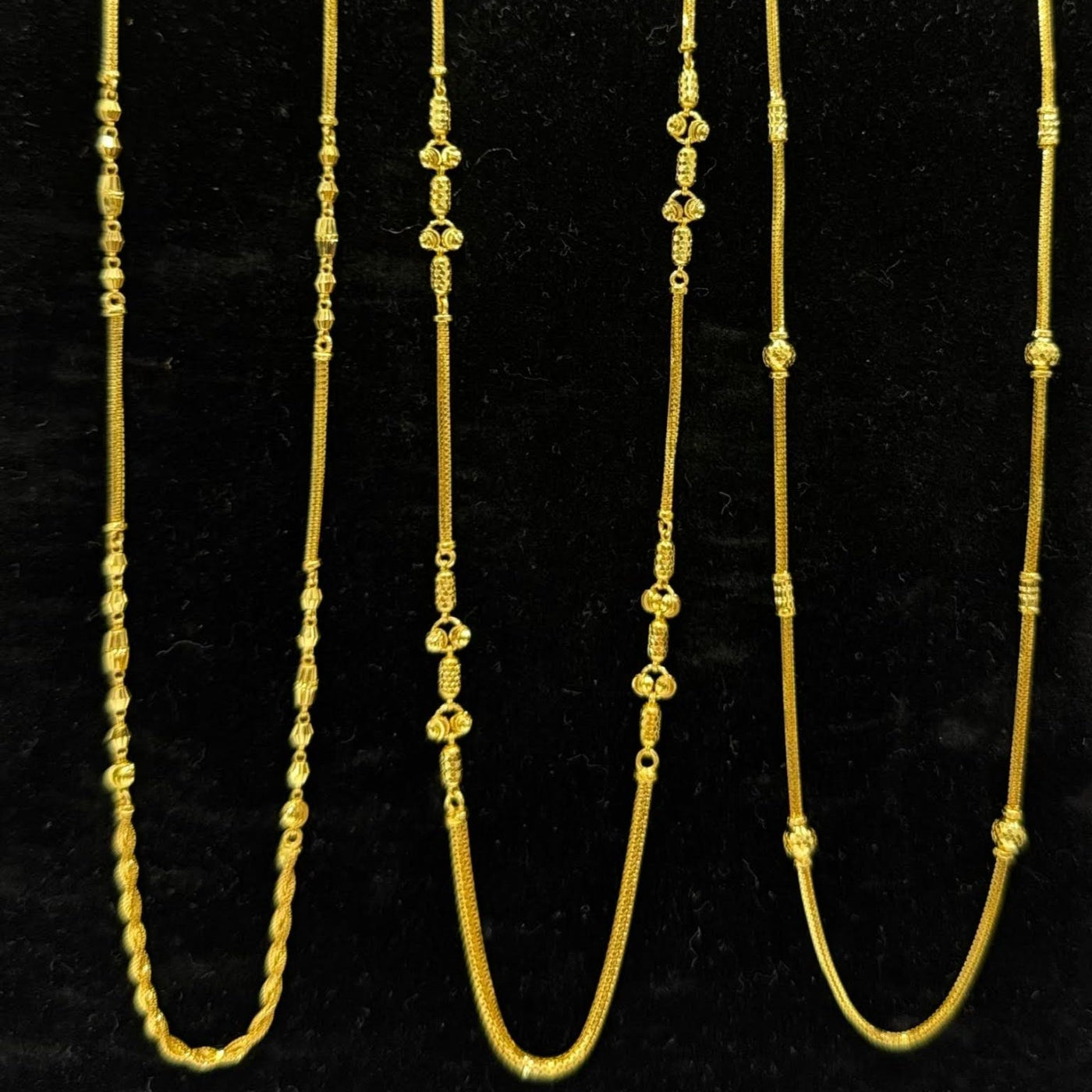 Three gold necklaces on a black stand