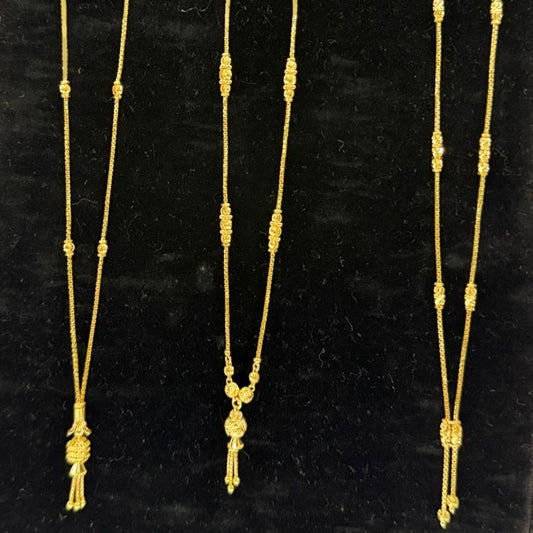 Three gold necklaces on a black stand