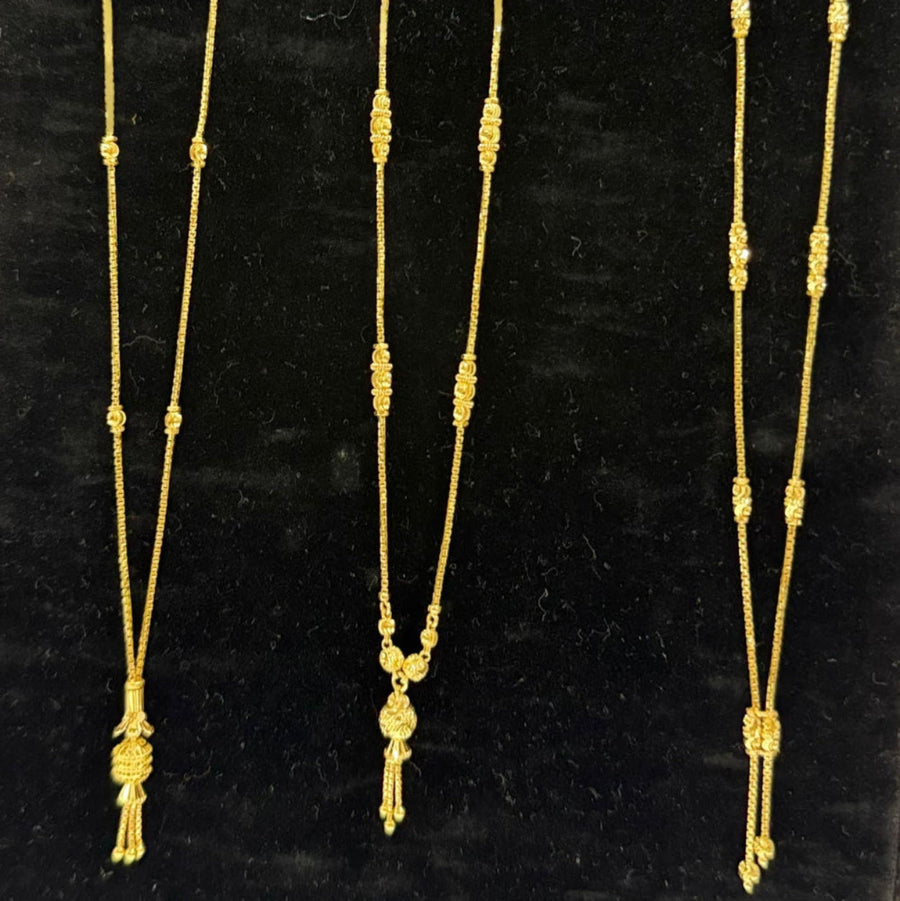 Three gold necklaces on a black stand