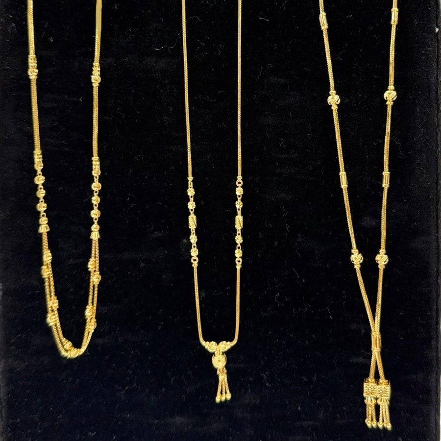 Three gold necklaces on a black stand