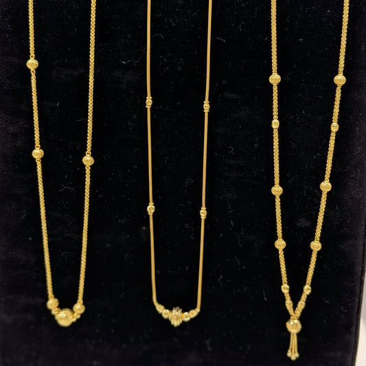 Three gold necklaces on a black stand