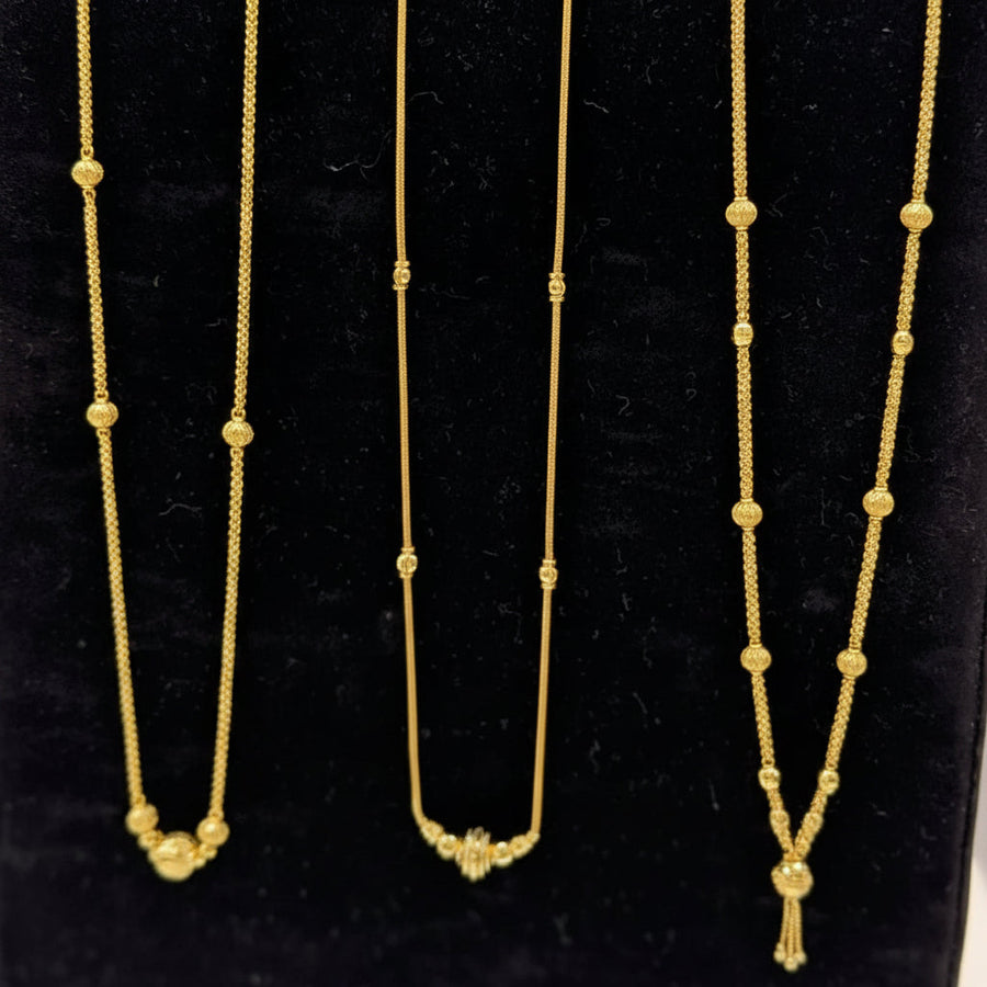 Three gold necklaces on a black stand