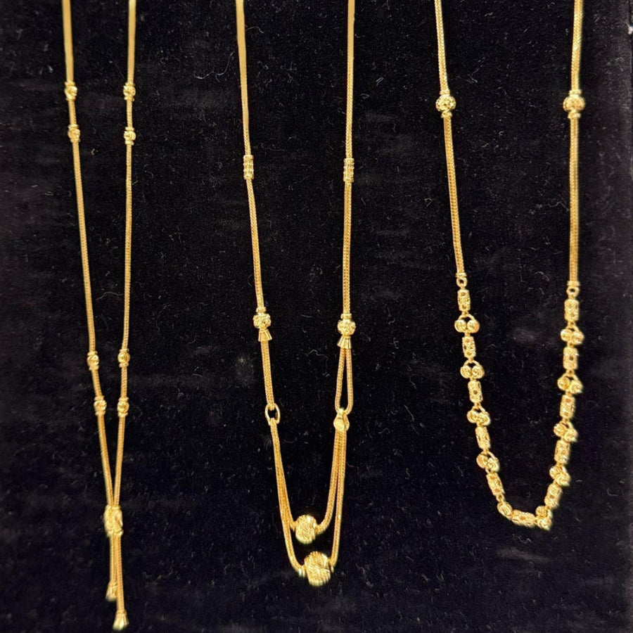 Three gold necklaces on a black stand