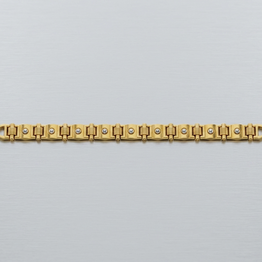 A gold-plated link bracelet with small clear stones set into the center of each link, displayed horizontally on a light gray textured background.