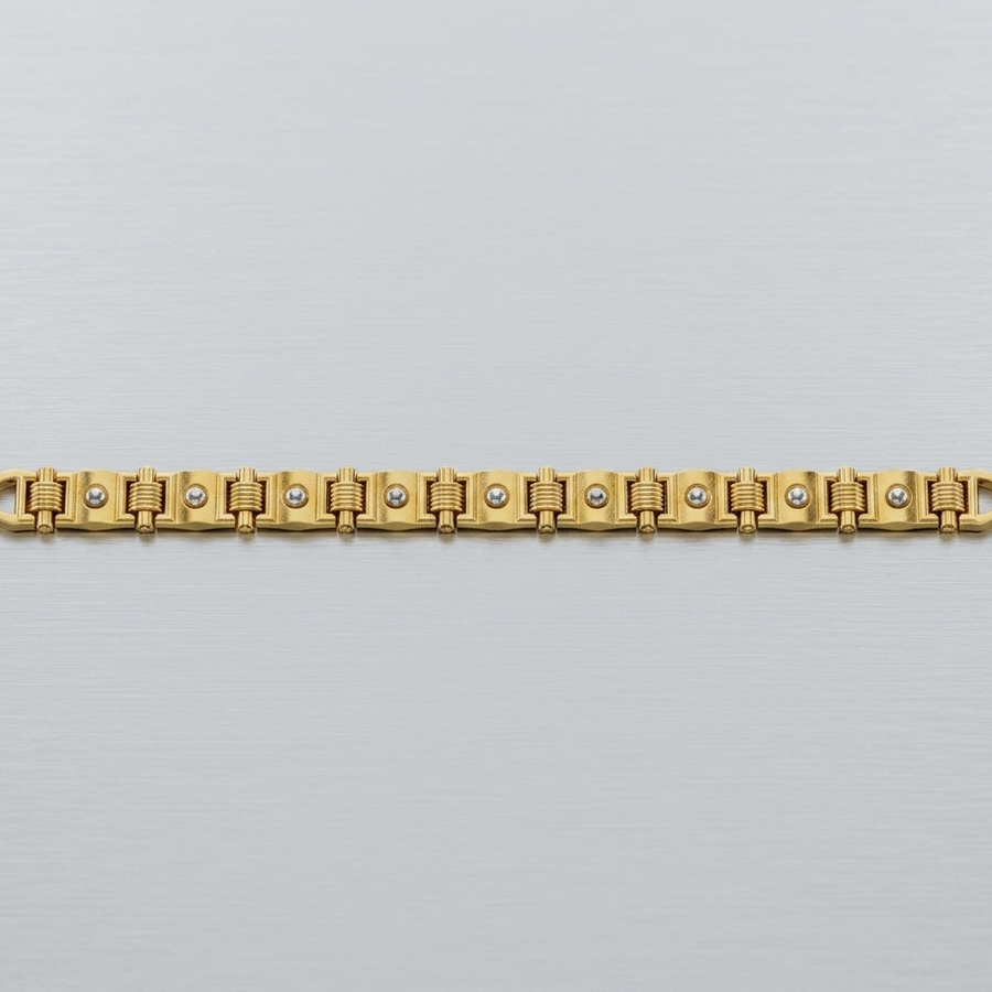 A gold-plated link bracelet with small clear stones set into the center of each link, displayed horizontally on a light gray textured background.