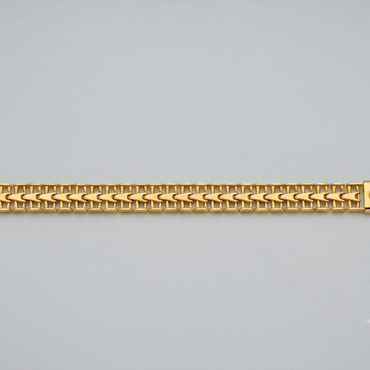 A gold-colored metal link bracelet with a woven chevron pattern, displayed horizontally against a neutral light gray background.