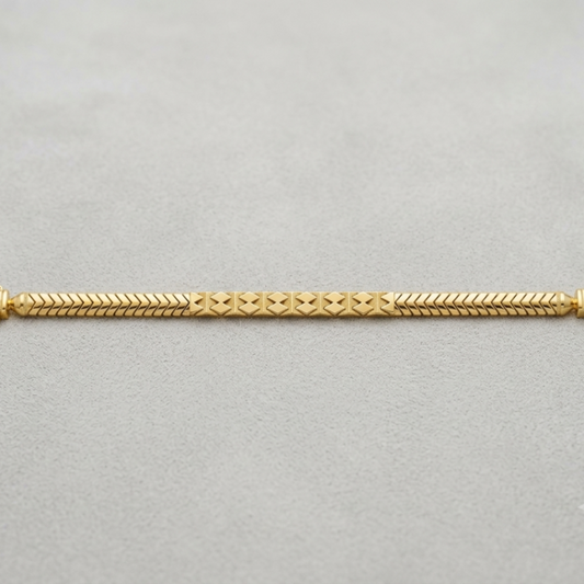 A gold chain bracelet with a textured, braided design and decorative end caps, displayed horizontally on a neutral gray background.