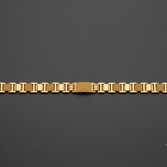 A gold-toned metal link bracelet with a textured center clasp, displayed horizontally on a dark gray background.