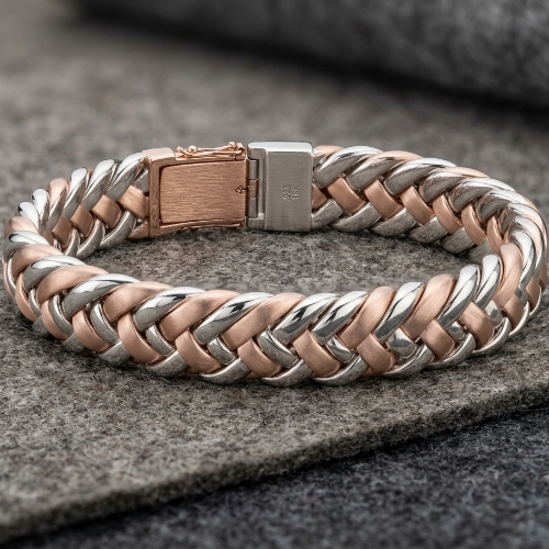 A braided metal bracelet with alternating silver and rose gold links, featuring a rectangular clasp, displayed on a textured gray felt surface.