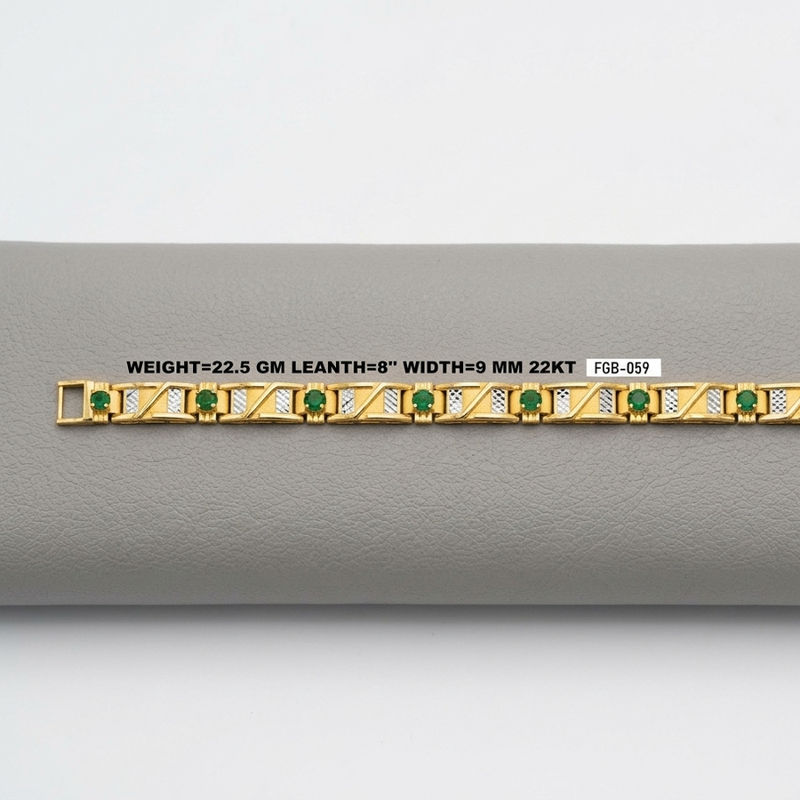 A gold bracelet with green emerald-cut stones and gold geometric detailing, displayed horizontally on a gray textured surface with a white label showing specifications.