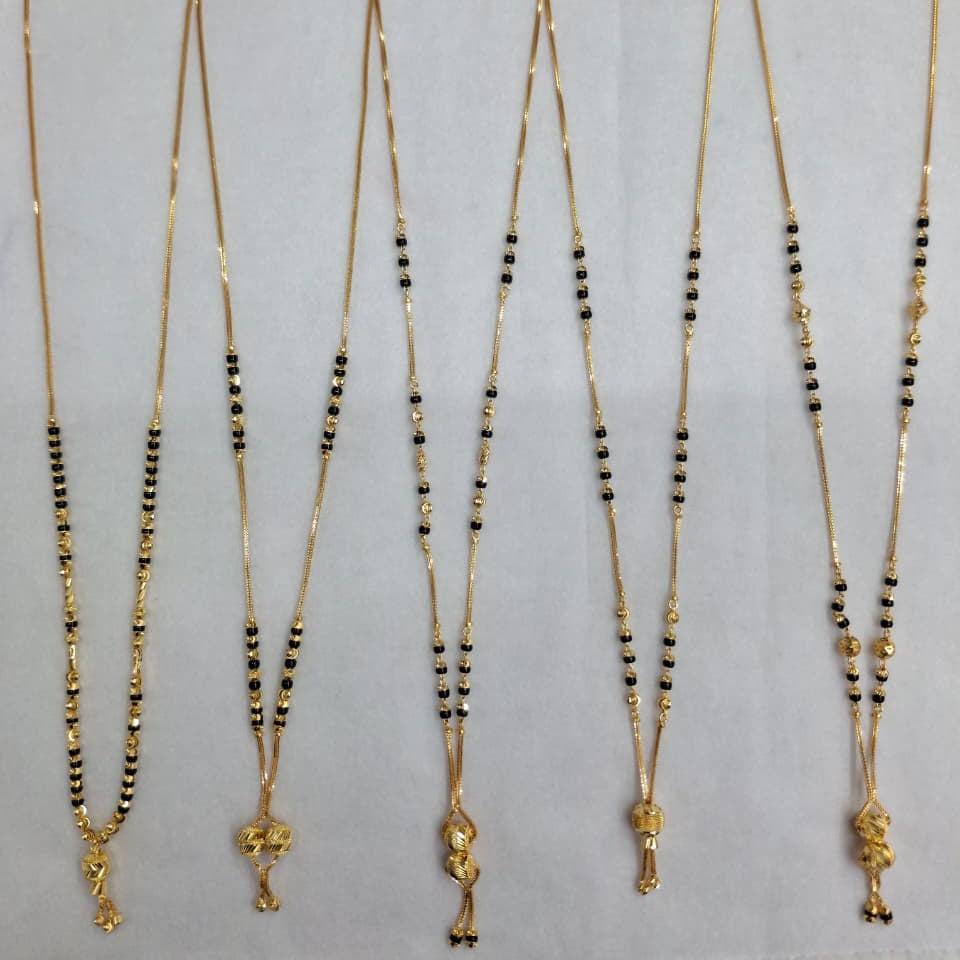 Set of five gold necklaces with black beads on a gray background