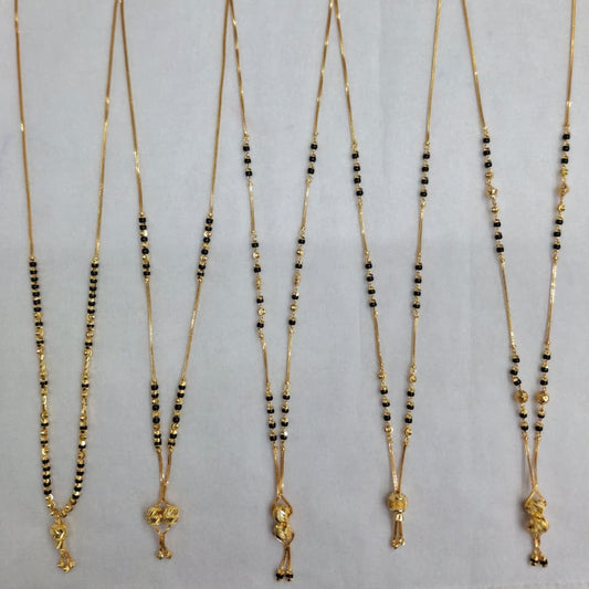 Set of five gold necklaces with black beads on a gray background