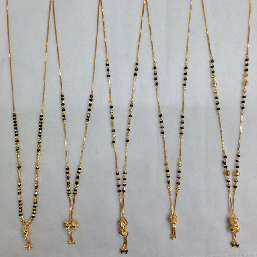Set of five gold necklaces with black beads on a gray background
