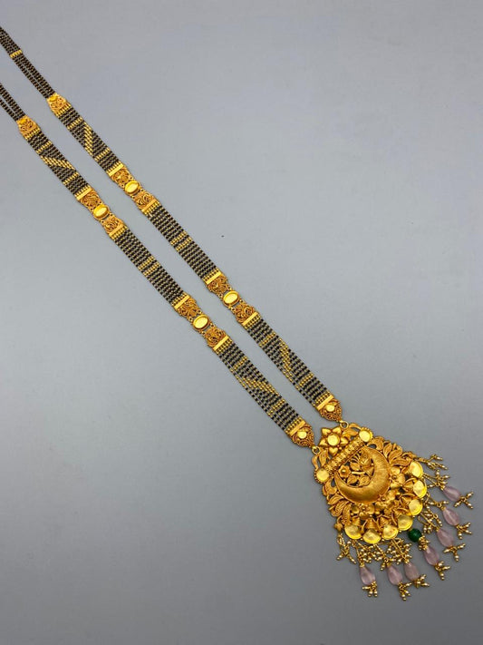 Gold necklace with a decorative pendant on a gray background
