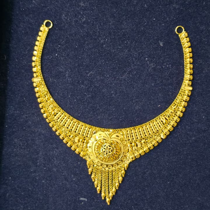 A gold-toned traditional Indian choker necklace with intricate filigree and beadwork, displayed on a dark navy velvet jewelry box.