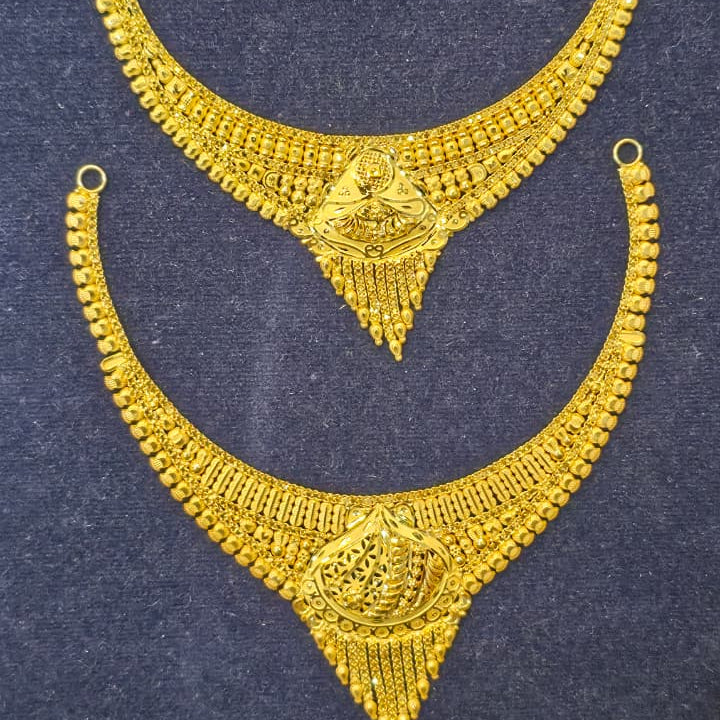 A pair of gold crescent-shaped traditional Indian jewelry pieces, likely waist chains or decorative necklaces, displayed on a dark textured background.