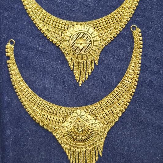 A pair of ornate gold-toned traditional necklace sets displayed on a dark blue velvet surface. The top necklace is a wide curved collar-style necklace with a circular central motif and dangling fringe.
