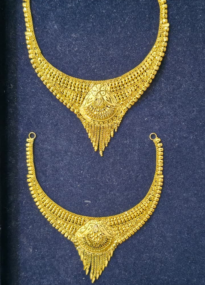 A pair of ornate gold-toned necklace pendants displayed on a dark blue velvet jewelry box insert.