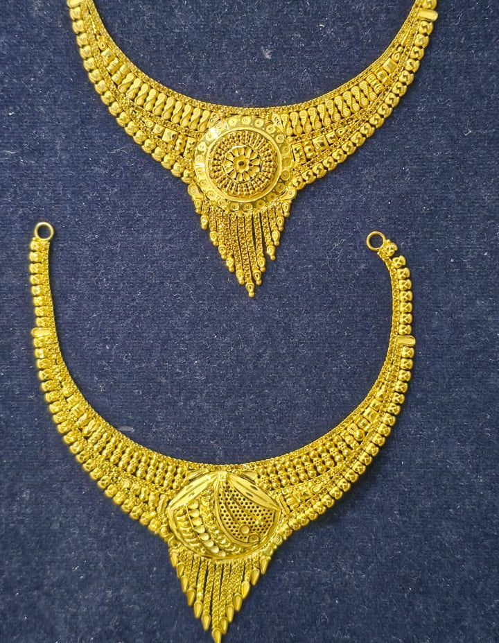 A pair of ornate gold crescent-shaped traditional jewelry pieces with intricate filigree detailing, displayed on a dark textured background.