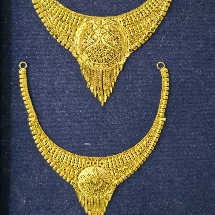 A pair of ornate gold-toned traditional necklace pieces displayed on a dark navy velvet jewelry box insert.