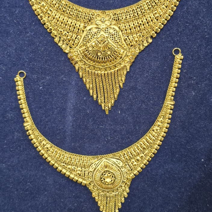 A pair of ornate gold-toned traditional necklace pieces displayed on a dark blue velvet background. The set includes a larger choker-style necklace at the top and a matching larger pendant necklace at the bottom, both featuring intricate filigree, beadwork, and dangling fringe details.