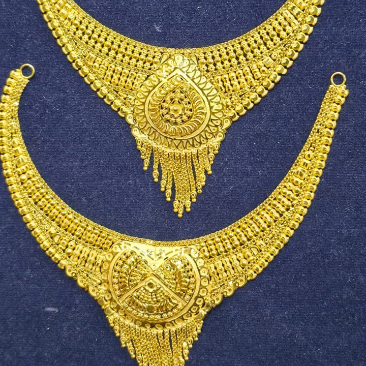 A pair of traditional Indian gold-toned jewelry pieces, likely a necklace and matching collar or choker, displayed on a dark blue velvet surface.