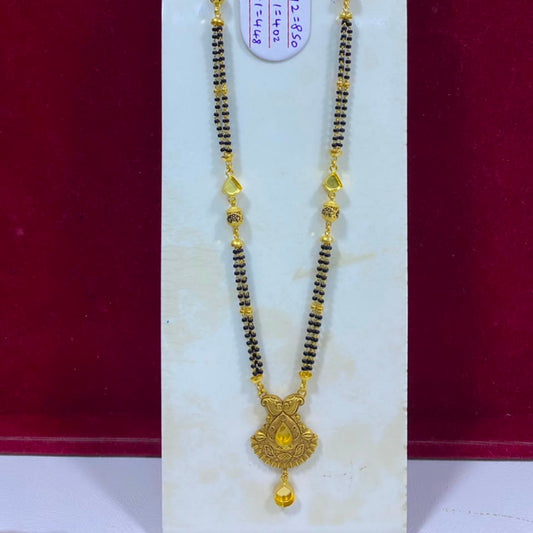 A traditional Indian gold and black beaded necklace (Murugai) with a detailed gold pendant, displayed on a white jewelry stand against a dark red background.