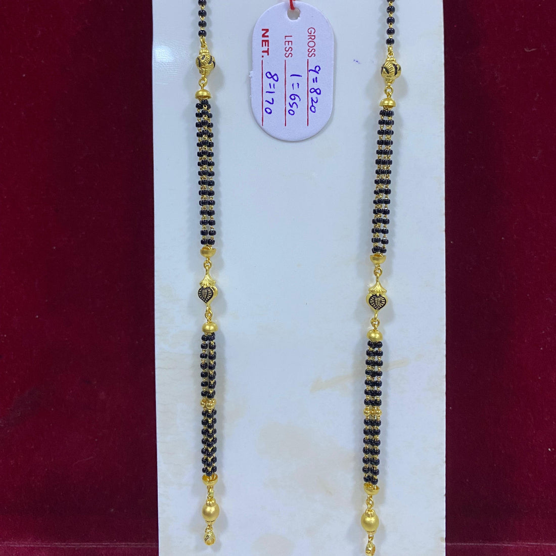 Two beaded necklaces with gold accents on a white card with a red background