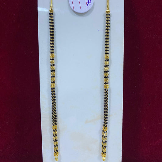 Two gold and black beaded hair strands on a white card with a red background
