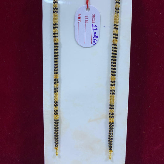 Two gold and black beaded necklaces on a white card with a red background