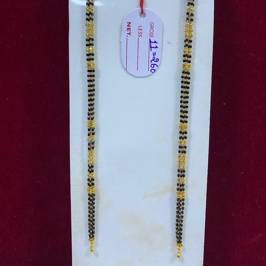 Two gold and black beaded necklaces on a white card with a red background
