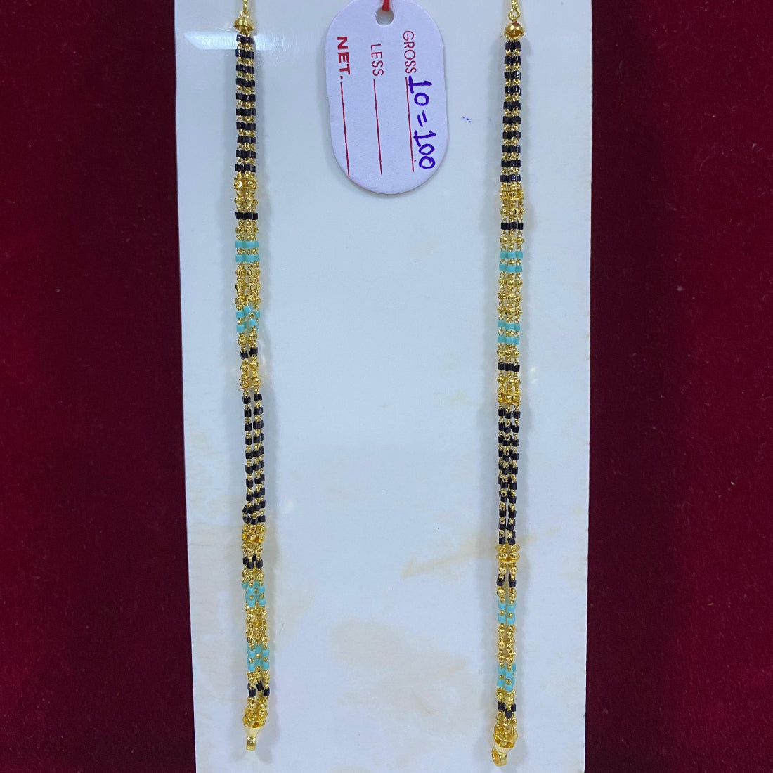 Two beaded bracelets on a white card with a red background