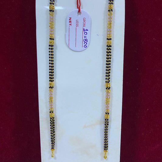 Two gold and black beaded bracelets on a white stand with a red background