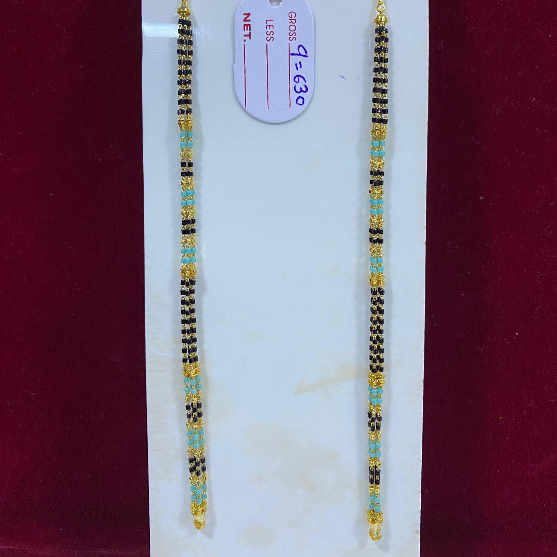 Two beaded bracelets on a white card with a red background