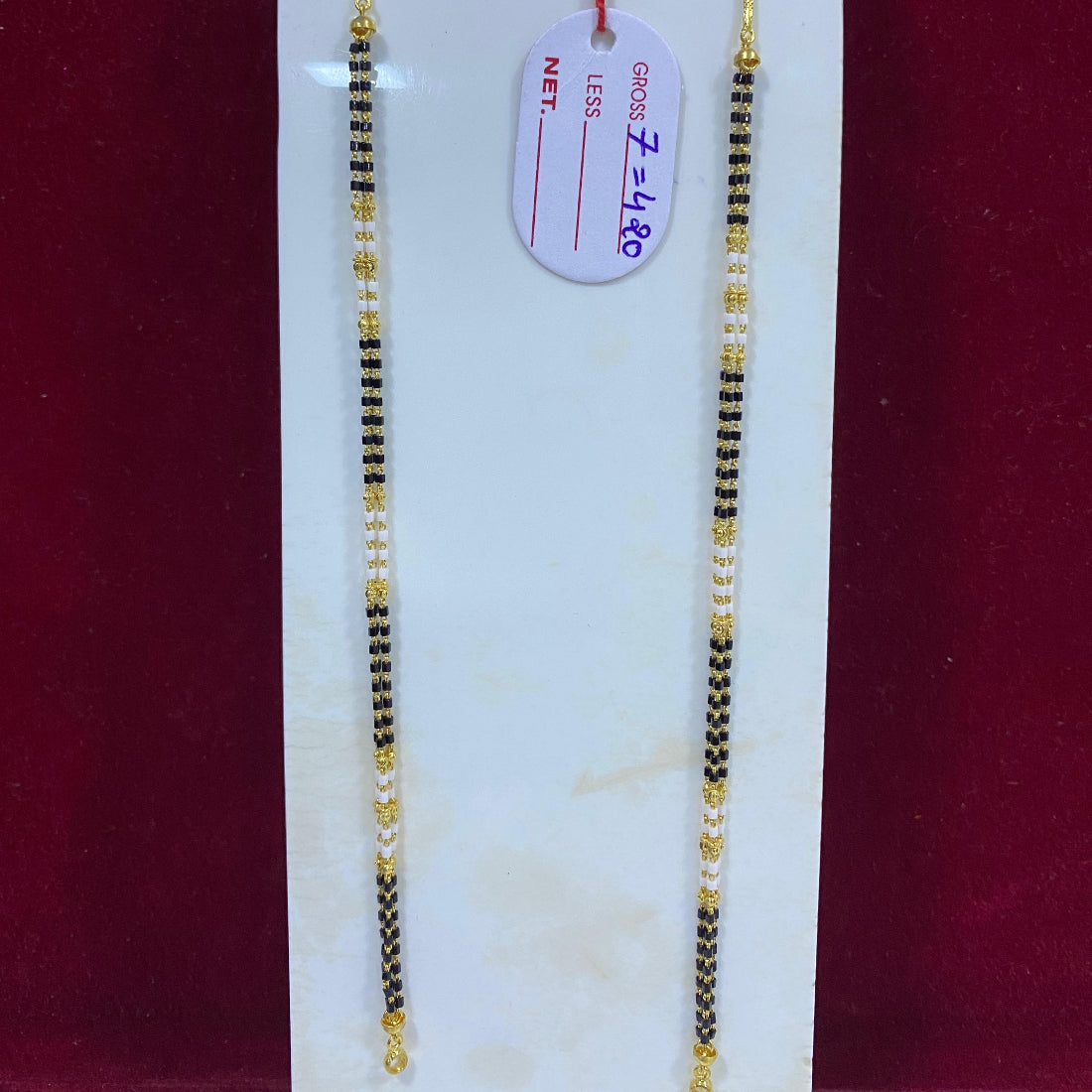 Two gold necklaces on a white card with a red background