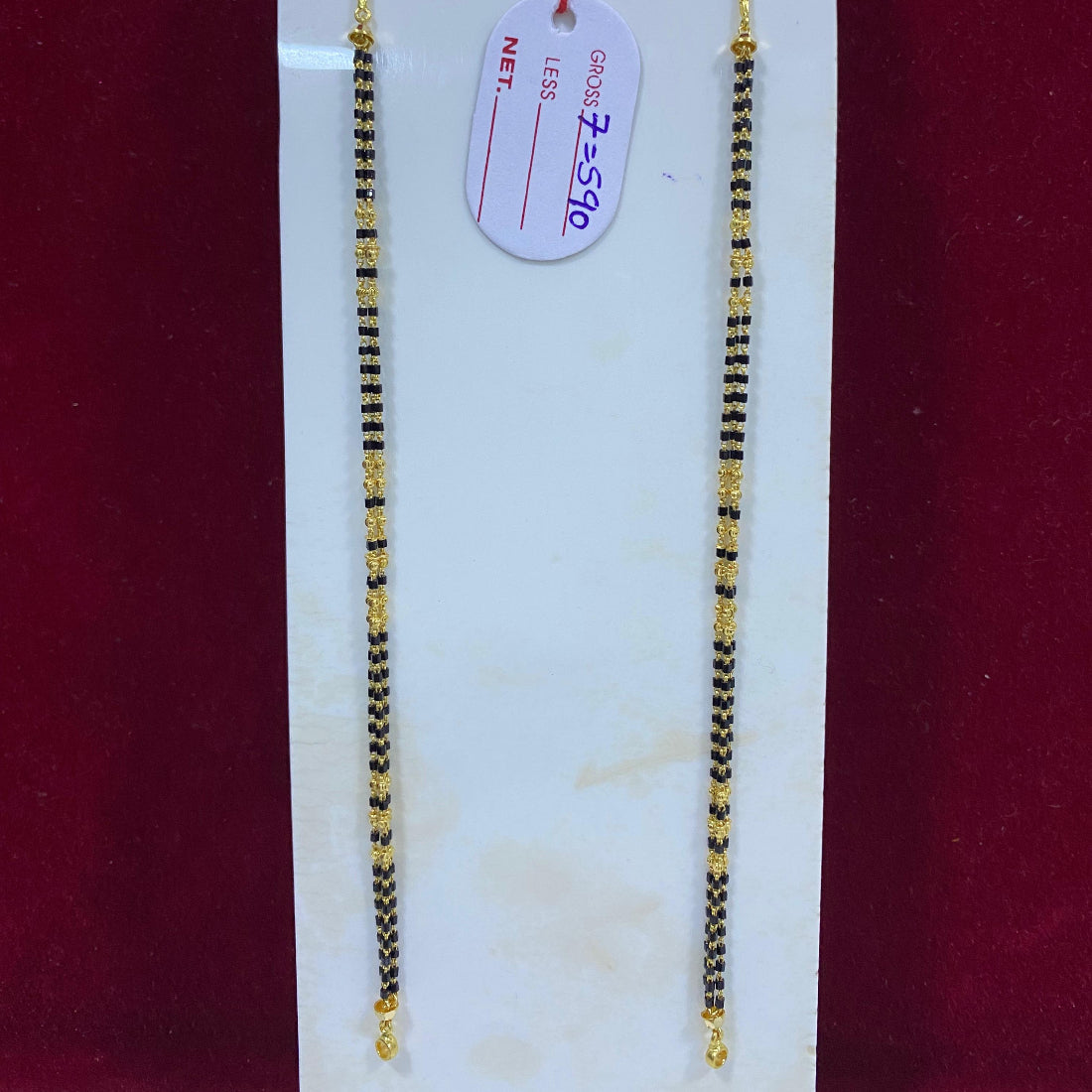 Two gold necklaces on a white card with a red background