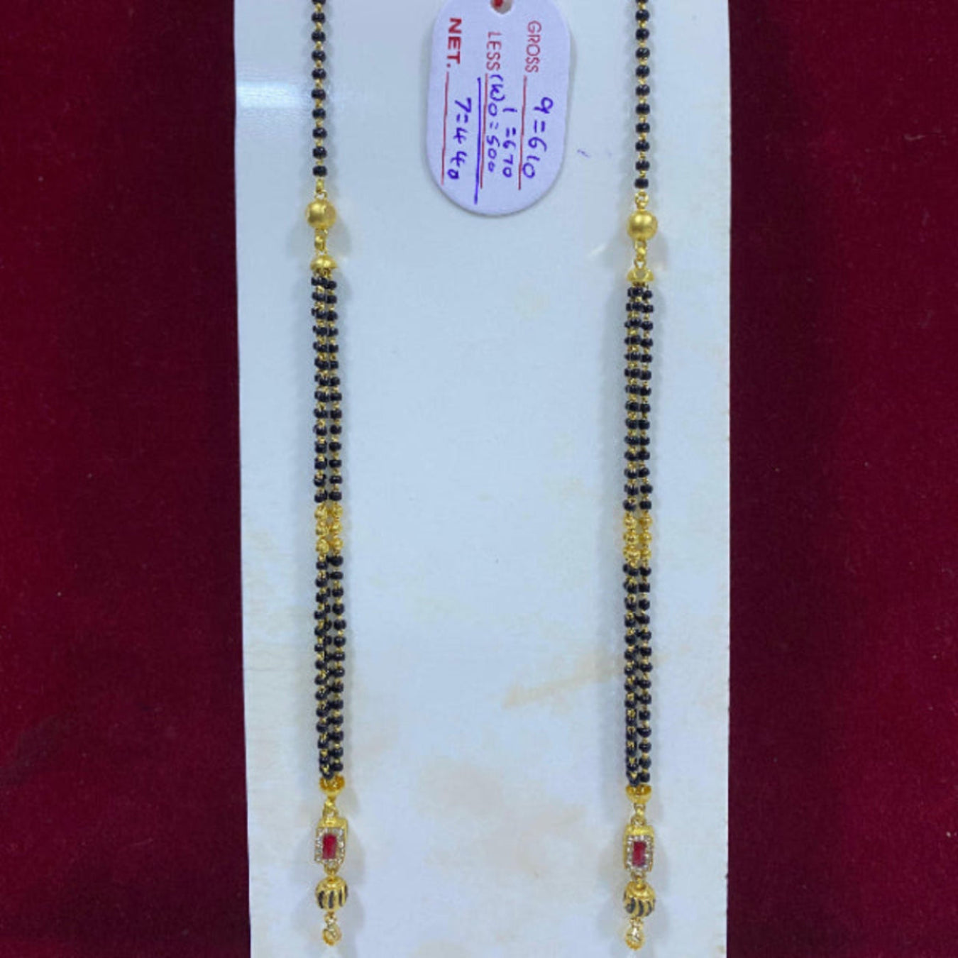Two gold necklaces on a white card with a red background