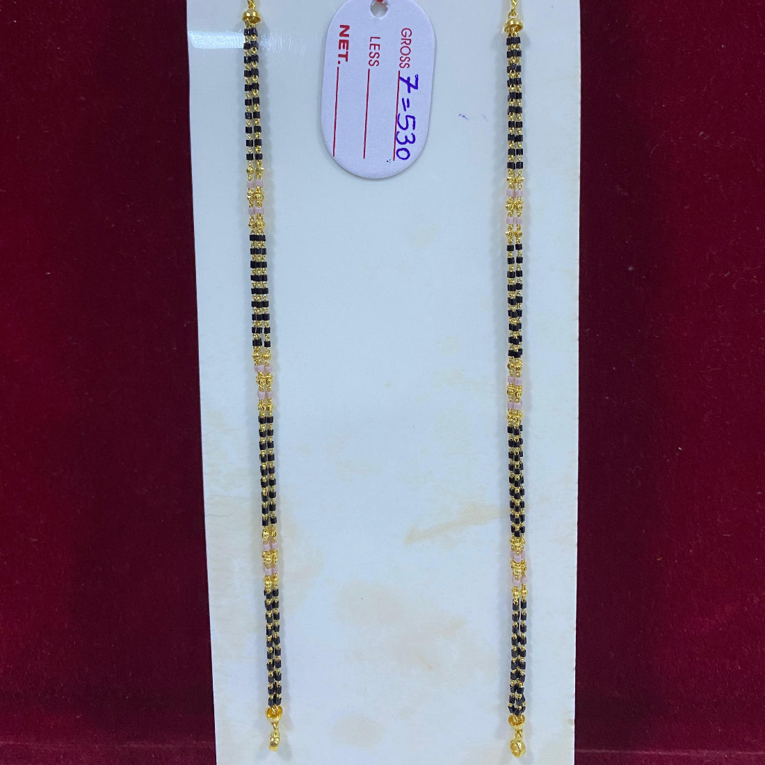 Two gold necklaces on a white card with a red background