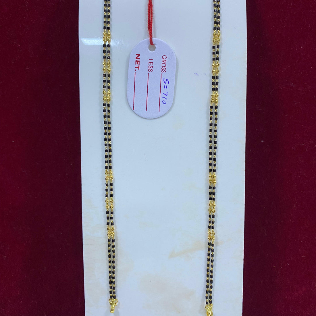 Two gold necklaces on a white card with a red background