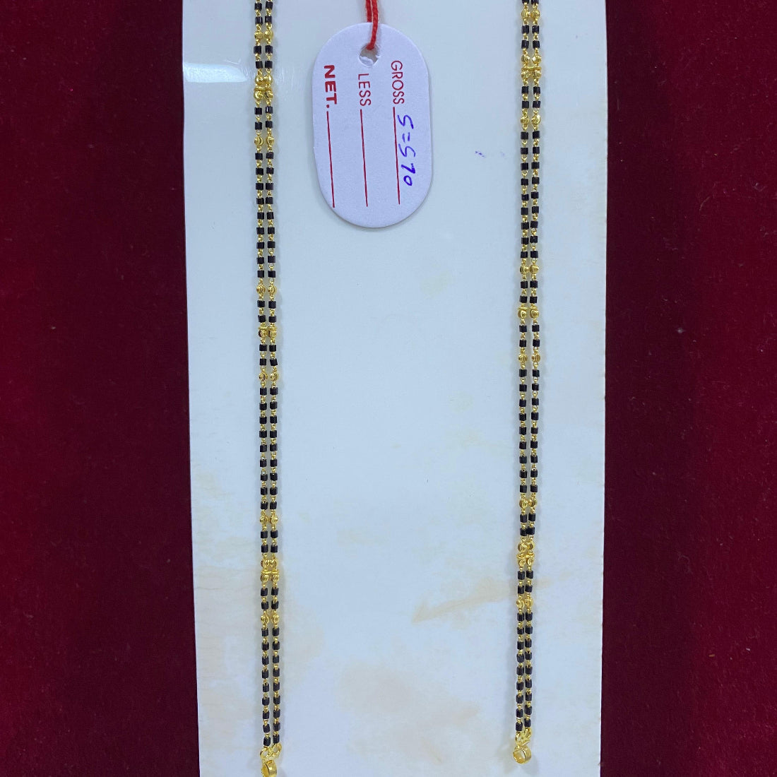 Two gold chains on a white card with a red background