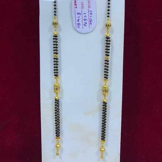 Two black beaded necklaces with gold accents on a white card against a red background.
