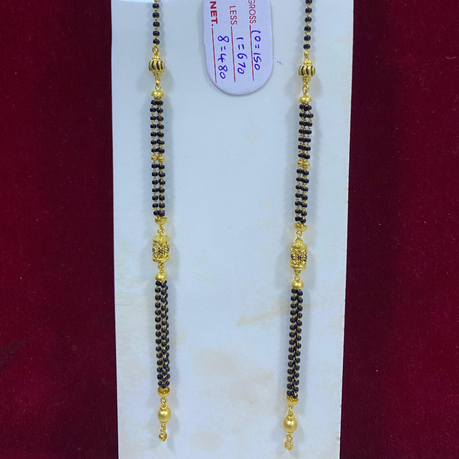 Two black beaded necklaces with gold accents on a white card against a red background.