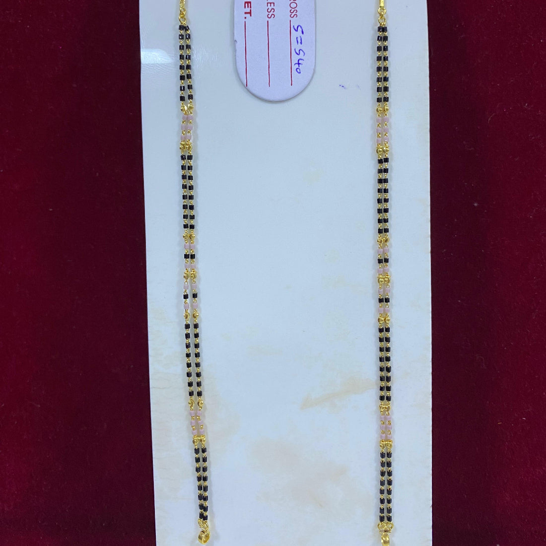 Gold necklace on a white card with a red background